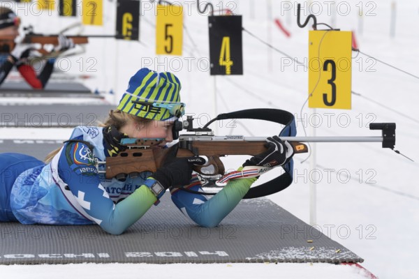 Sportswoman biathlete Anastasia Legostaeva rifle shooting in prone position. Biathlete in shooting range of Open regional youth biathlon competitions East Cup. Kamchatka, Russia, April 12, 2019, Europe