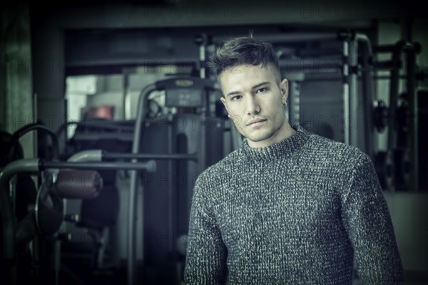 Handsome white asian young man wearing grey sweater, standing indoor in dark place