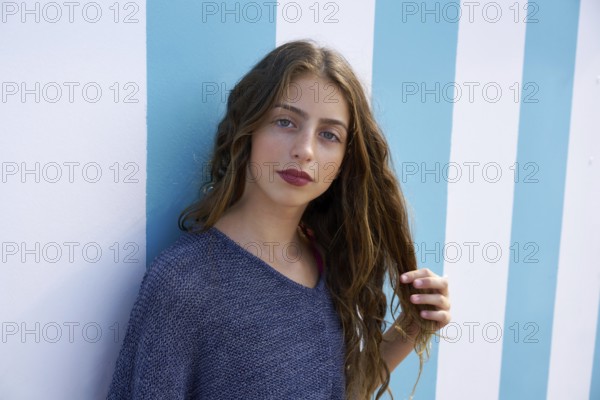 Brunette teen girl portrait in a summer beach blue stripes wall
