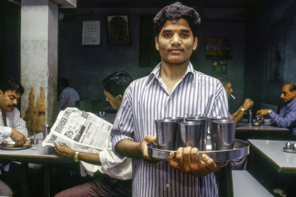 Waiter serving drinking water steel glasses, Udipi restaurant, Mumbai, Maharashtra, India, Asia