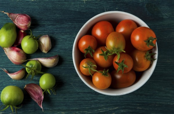Tomatoes on the background. Tomatoes, garlic on a wooden surface. View from above. Fresh vegetables. copy space
