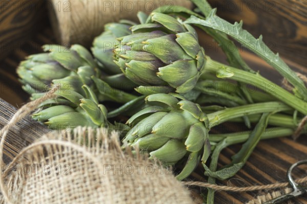 Two artichoke bouquets on kitchen table among some kitchen items. Top view