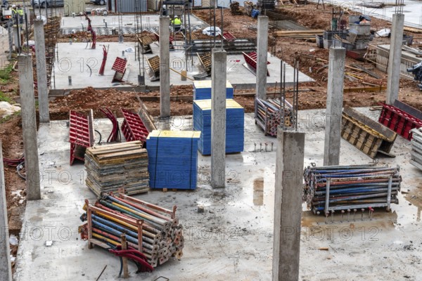 Construction site with reinforced concrete columns and galvanized steel struts and wooden structural formworks stacked ready for the construction of a new floor