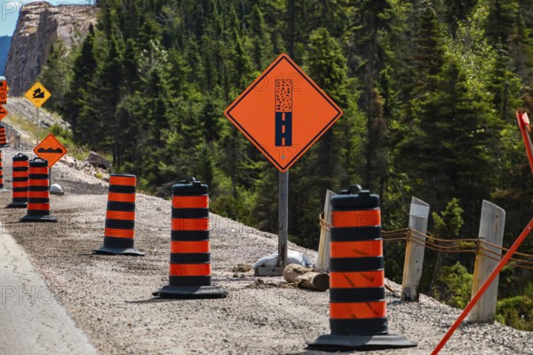Paved surface ends ahead orange sign, Temporary condition road signs barrels, warning symbols, on the right roadside, under construction asphalt road