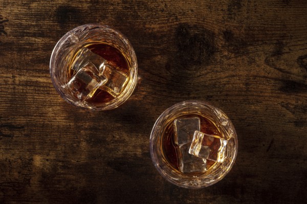 Whiskey in glasses with ice. Bourbon whisky on rocks on a dark rustic wooden background, overhead flat lay shot, Food photography, Food photography