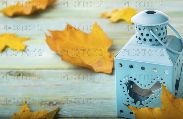 Candlestick and yellow maple leaves on a turqoise wooden table