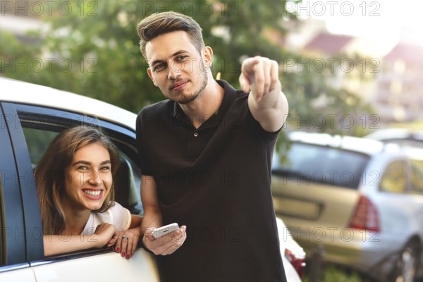 Beautiful girl sitting in the car and flirting with guy who outdoor standing