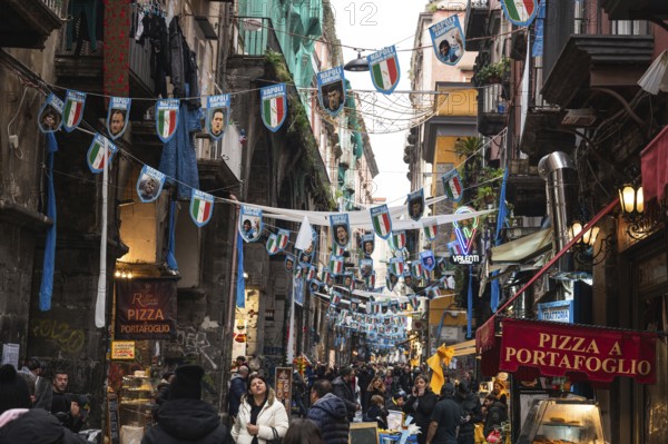 NAPLES, ITALY - JANUARY 14, 2024: A street with the pennants of the football team FC Napoli, the champion of Italy and crod of people below