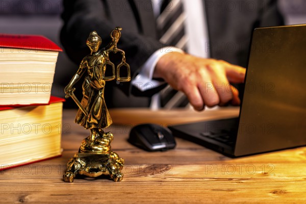 Office of a lawyer with books and a statue of Lady Justice, goddess Justitia, on the desk