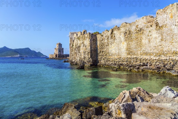 The watchtower is built on long cape in the sea. Sea shoal beautiful azure color. Venetian fort castle Methoni. The concept of active, photo and historical tourism