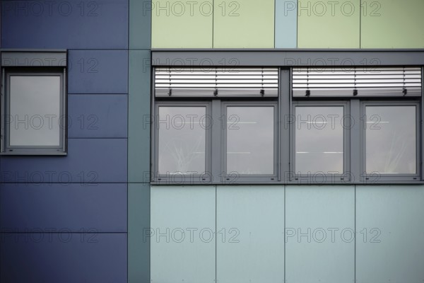 The modern façade of an office building with rows of windows and metal blinds