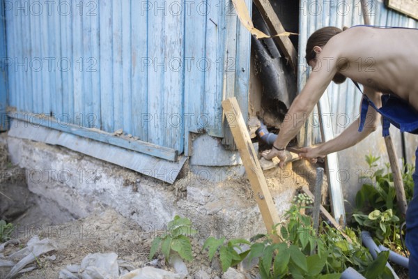 A man repairing the exterior corner of a wooden building