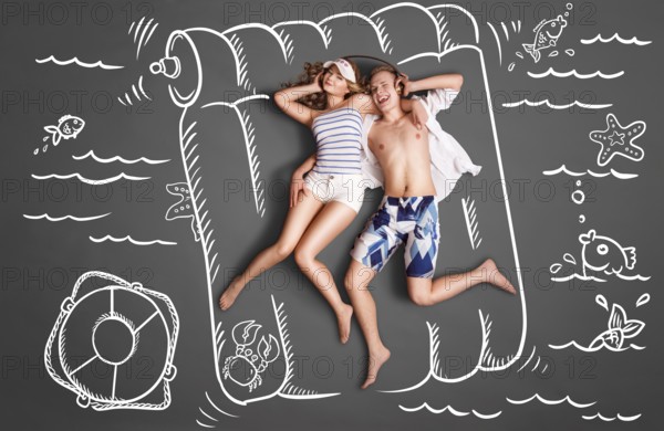 Happy valentines love story concept of a romantic couple lying on an air mattress, sharing headphones, and listening to music against chalk drawings pool background