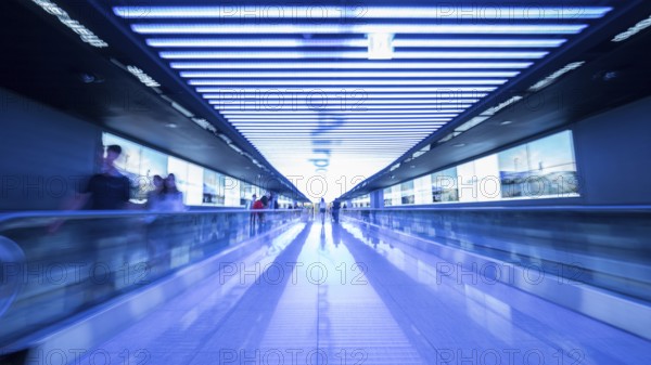 People going in walkway and riding flat escalators at the airport of Seoul, South Korea. Futuristic blue toned shot