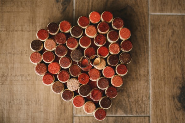 Wedding rings of the bride and groom on a pattern of hearts made of wine bottle corks on a wooden texture.