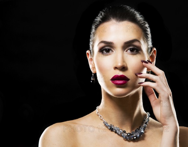 Romantic woman with dramatic makeup and nailpolish. Big blue silver fashion necklace. Black background, Toronto, Canada, North America
