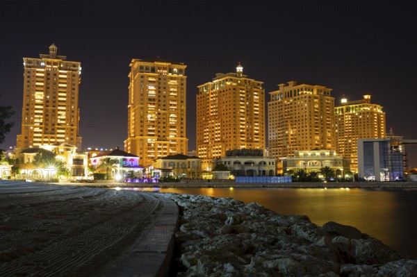 The skyline panorama of The Pearl-Qatar area buildings in Doha, Qatar at night. The Pearl-Qatar is an artificial island spanning nearly four square kilometers. Long exposure