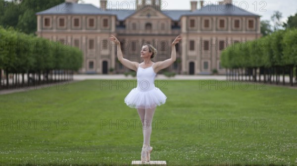 Ballerina in a white tutu dancing in the park of a palace, surrounded by green trees and symmetrical layout, Favorite Palace, Rastatt, Baden-Württemberg, Germany, Europe