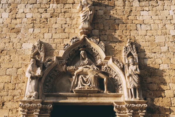 Facade of the Franciscan monastery with high relief depicting holy images in the old town of Dubrovnik, Croatia.
