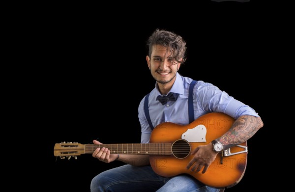 Handsome young man in bow-tie with guitar looking at camera.Studio shot