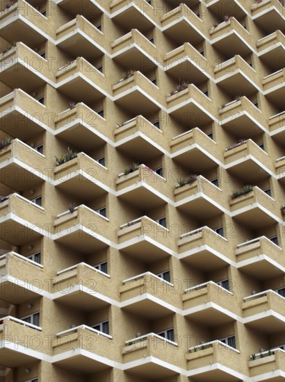 Large highrise modern apartment building with large number of repeating geometric balconies in stone yellow colors