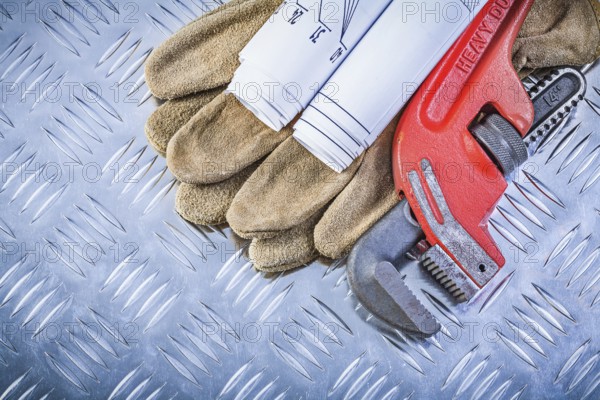 Assortment of pipe wrench engineering drawings leather protective gloves on fluted metal sheet building concept