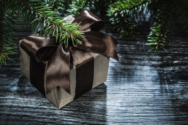 Gift box with ribbon pine branches on wooden board
