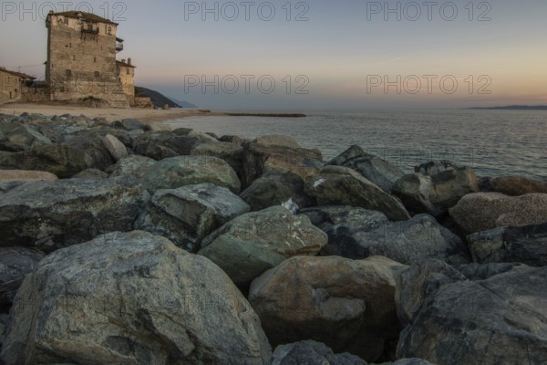 View over the sea into the sunset. Landscape taken with the historical landmark of the Byzantine tower of Prosphorion on the coast of Ouranoupoli, Thessaloniki, Central Macedonia, Greece, Europe
