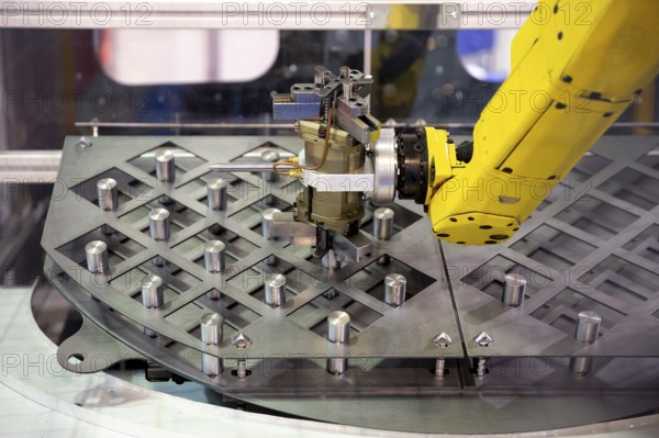 Yellow robotic arm arranges metal elements after being produced. Automatic industrial machinery equipment