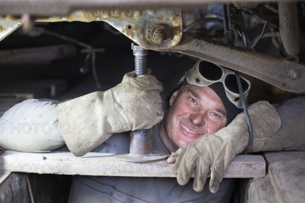 A male car mechanic repairs a car in a garage