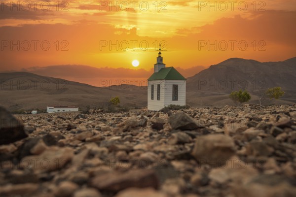 Small, sweet white wooden chapel in a barren volcanic landscape. Sunset, landscape shot of the church Ermita Protestante de Violante on the island of Fuerteventura, Canary Islands, Spain, Europe