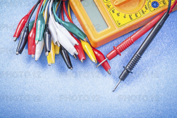 Crocodile plugs digital multimeter on blue background top view electricity concept
