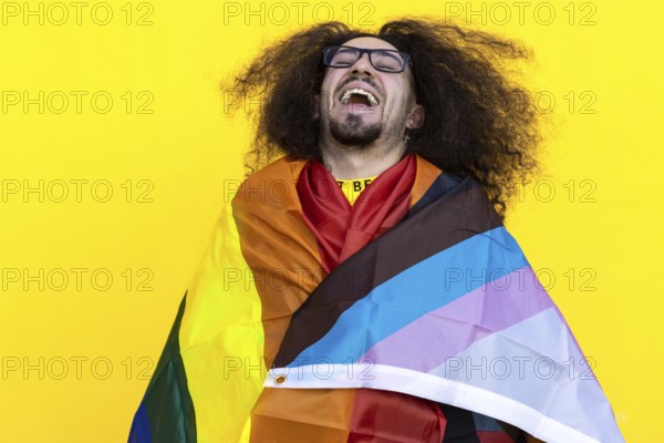 Happy smiling gay man wrapping with a rainbow lgbt flag