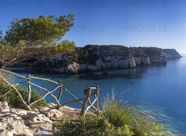 A landscape view of the idyllic Cala Macarella in southern Menorca with a hiking trail in the foreground