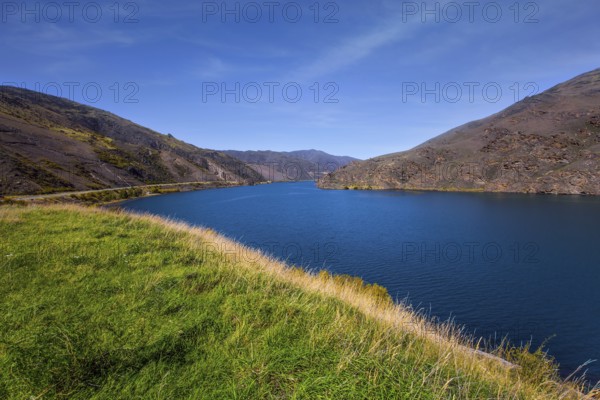 The surroundings of the city of Cromwell among mountains and lakes. Blue sky and light clouds. New Zealand Southern Alps. The concept of ecological, landscape and photo tourism