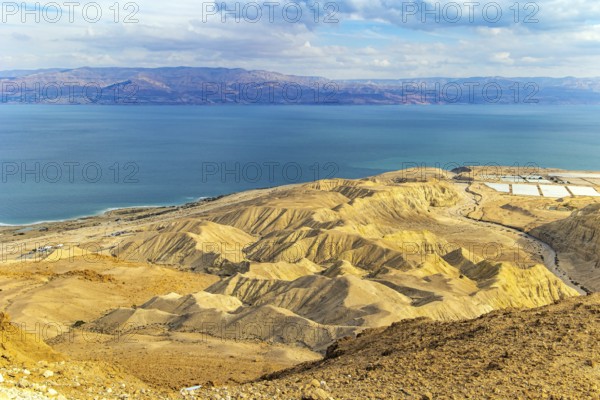 Israel. The great wonder of nature is the Dead Sea. Cloudy and clear January day. The sea surface reflects the clouds. Jordan on the opposite coast of the sea is illuminated by the dim winter sun