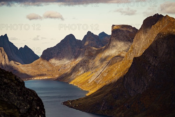Dramatic view of a fjord with towering mountains casting shadows along the landscape, mountains, rocks, road, sea, ocean, water, nature, couds, vilage, Lofoten Islands, Norway, Norge, Europe