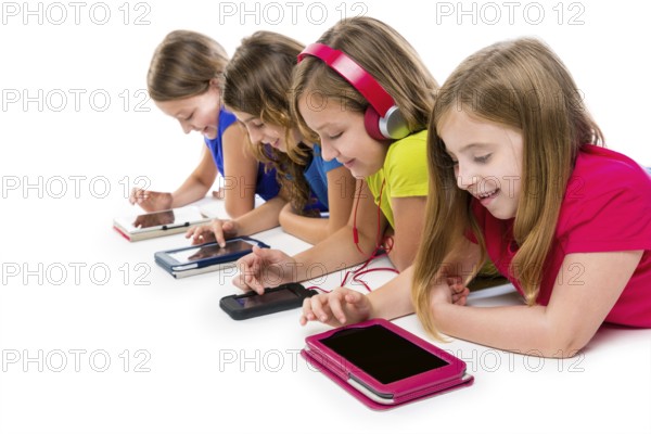Sisters cousins kid girls with tech tablets and smatphones in a row lying on white background