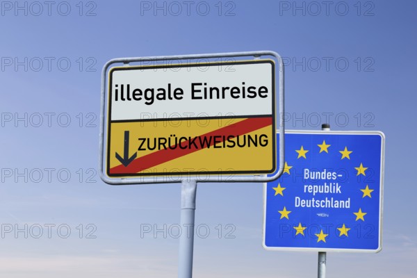 (Photomontage) Town exit sign with the inscription ILLEGAL ENTRY / REFUSAL in front of a border sign of the Federal Republic of Germany