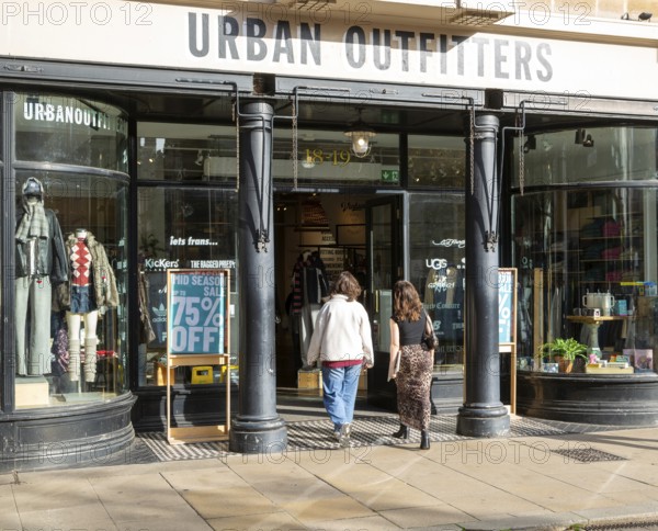 Urban Outfitters clothes shop store in city centre, Cambridge, Cambridgeshire, England, UK two women entering door