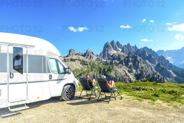 Family relaxing in camping chairs, enjoying breathtaking view of tre cime di lavaredo, dolomites, italy, during summer vacation with their camper van