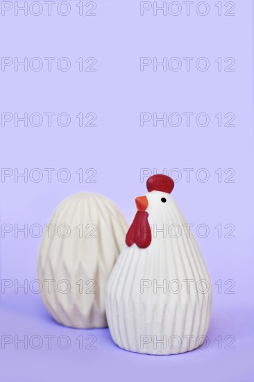 Ceramic Easter chicken and egg decoration objects on purple background with copy space