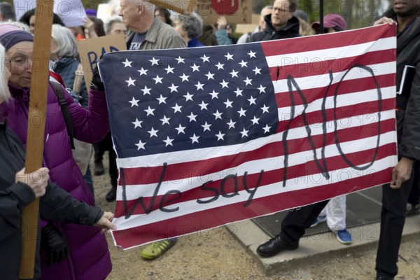 Berlin, Germany - 5 April 2025: Demonstrators protest against the policies of US President Donald Trump and his advisor, Tesla owner Elon Musk, with an American flag with the inscription We say NO in front of the US Embassy in Berlin under the slogan Hands Off