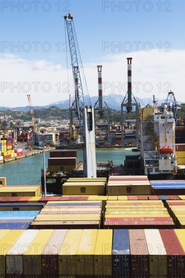 High angle view of stacked rectangular metal box shipping containers and gantry cranes on dock in La Spezia cargo Port, Italy, Europe