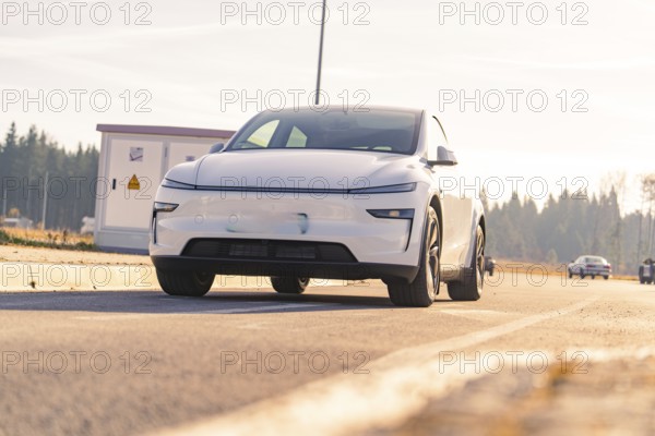 Modern white car on an asphalt road with natural landscape in the background, Tesla, New Model Y Juniper, Germany, Europe