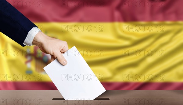 Hand holding ballot in the ballot box with the flag of Spain in the background. Spain general elections, voting concept