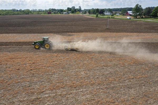 Hudson, Michigan, A cloud of dust blows behind the tractor as a farmer tills his field