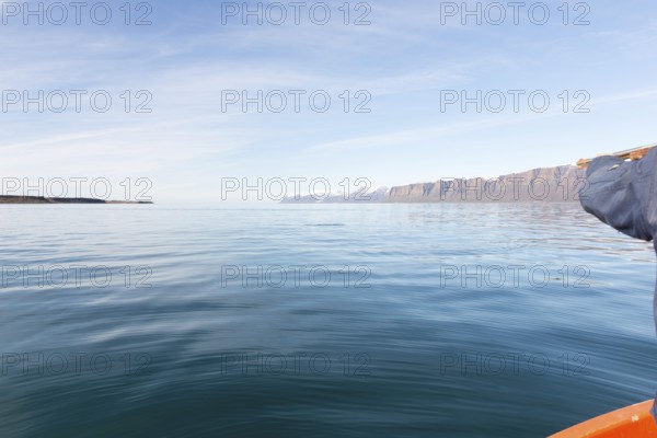 Greenlandic man hunting for seal in Greenland, pointing the gun towards the water, Greenland, North America