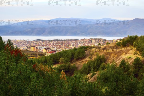 Aerial autumn morning view of Sandanski, Bulgaria with colorful forest trees and fog