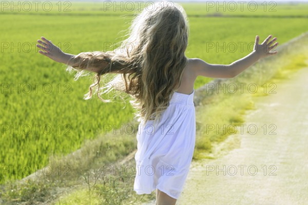 Rear view running open arms little happy girl green meadow field track
